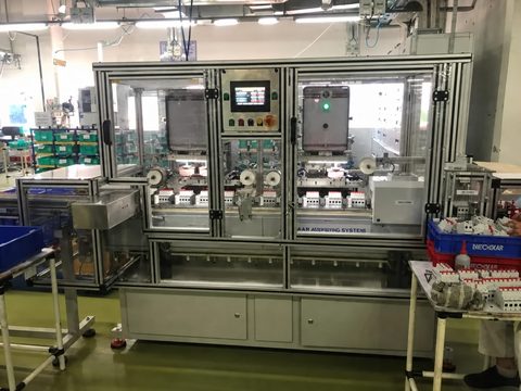 Enclosed two colour MCB automation line with guarded aluminium framing and a colour touchscreen HMI, printing MCB bodies on a customer floor